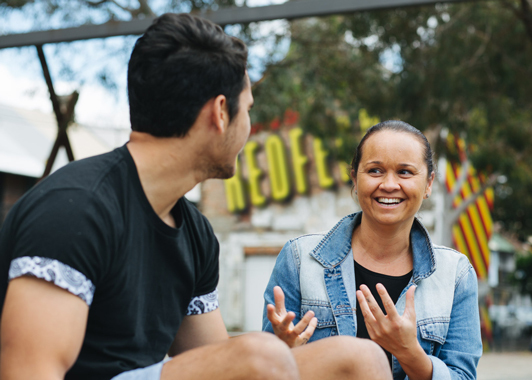 Adult and young person smiling and talking outside